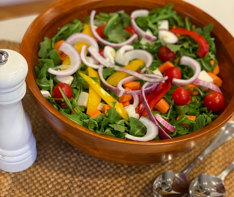 A salad served from an acacia bowl with mill and servers