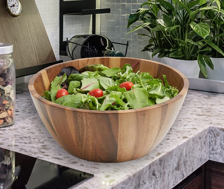 An acacia serving bowl of salad on a kitchen counter